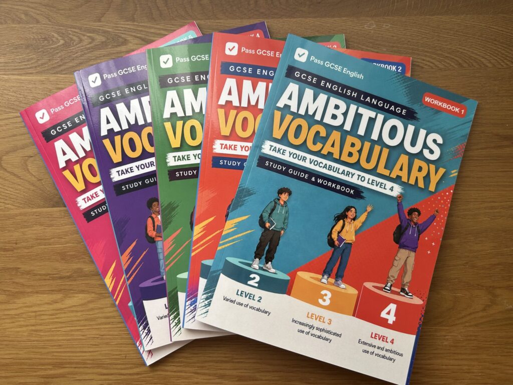 Five Ambitious Vocabulary GCSE English workbooks arranged on a wooden desk
